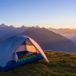 Backpacking tent at sunrise with sleeping bag inside overlooking a mountain landscape